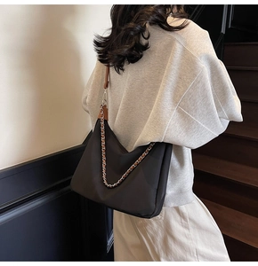 Detail der schwarzen Nylon-Hobo-Tasche mit geflochtener Kette und braunem Lederriemen