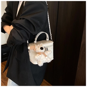 Detailed view of white woven box bag with silver hardware and a plush puppy charm