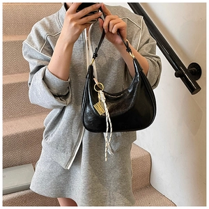 Detail of black wax texture hobo bag with pleated finish and gold hardware charm