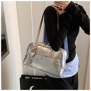 Mirror selfie showing the large silver metallic tote bag with bow and heart charms