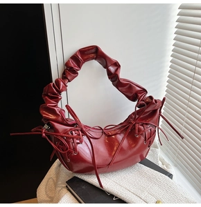 Détail du sac à bandoulière plissé bordeaux brillant avec un nœud chic en dentelle