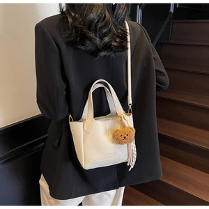 Detail of cream white lychee texture bucket bag with cute bear charm and silk scarf