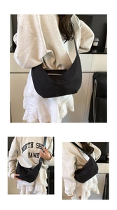 Close-up of minimalist black crescent hobo bag with wide shoulder strap and silver zipper