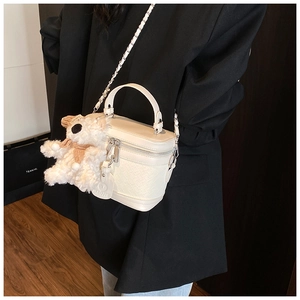 Detail view of cream mini box bag with leather weave texture and plush bear charm