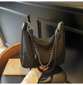Detailaufnahme einer schwarzen Hobo-Tasche mit silberner Metallkette und Nylon-Textur