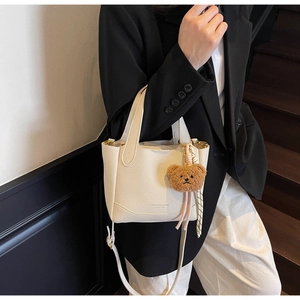 Close-up of beige lychee texture bucket bag with a cute brown teddy bear charm