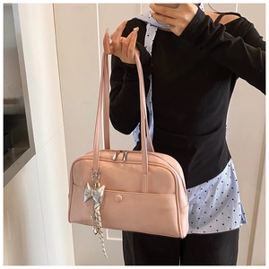 Close-up of soft pink oil wax leather Boston bag featuring a metal bow charm detail