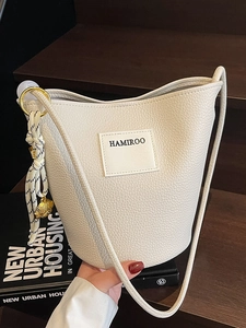 Sac seau minimaliste en cuir grainé beige avec bandoulière dans un cadre de vie quotidien