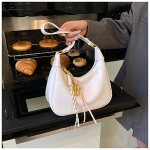 Detailed close-up of white wax leather tote bag with gold ring and fringe tassel