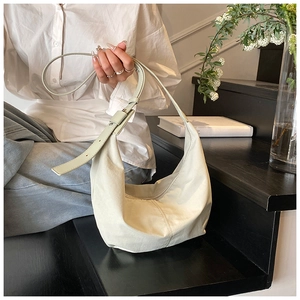Detail of minimalist cream crescent hobo bag with adjustable strap worn by a model