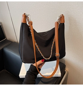 Detailansicht der schwarzen Nylontasche mit braunem Lederbesatz und silberner Kette