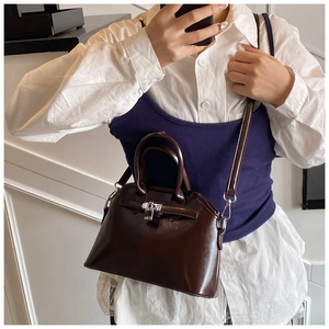 Mirror selfie showing a deep brown oil wax leather handbag with silver lock and top handle