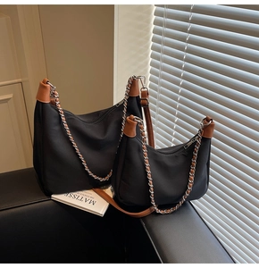 Makroaufnahme einer schwarzen Nylon-Tasche mit braunem Besatz und silbernem Kettenriemen-Detail