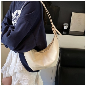 Detail of adjustable shoulder strap and smooth zipper on cream minimalist hobo bag