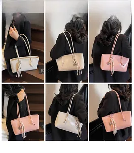 Detail of embossed brand logo and braided tassel pendant on stylish underarm bucket bags