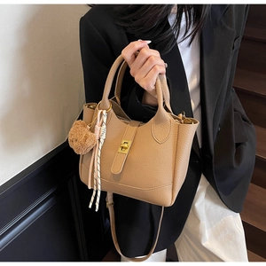 Detail of khaki lychee grain bucket bag with gold twist lock and cute bear charm decor