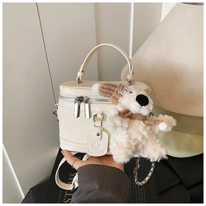 Detail of beige cylinder bag with woven texture, metal zipper and plush bear charm