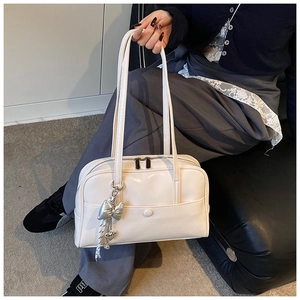 Detail of creamy white leather Boston bag with silver bow charm and dual zip closure