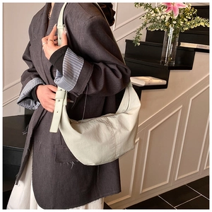 Minimalist cream crescent hobo bag shown with a model wearing a dark grey suit jacket
