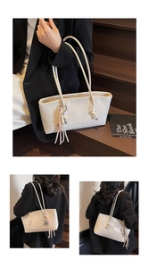 Minimalist beige tote bag with hanging tassel detail and embossed fashion lettering