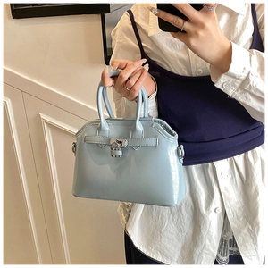 Detail of light blue glossy oil wax leather handbag featuring metal lock and top handles