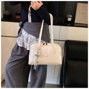 Detail view of cream white oily leather Boston bag with stylish silver bow charm accessory