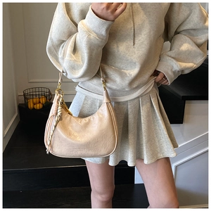 Detail of off-white oiled leather crescent bag with unique woven tassel and zipper