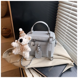 Detail view of grey box bag with woven texture leather and cute plush bear charm