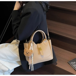 Khaki lychee leather bucket bag with retro metal buckle and plush bear charm detail