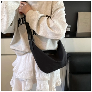 Close-up of black half-moon hobo bag with silver zipper and wide strap in daily style