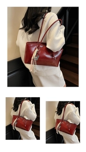 Close-up of wine red glossy leather shoulder bag with embossed text and woven tassel detail
