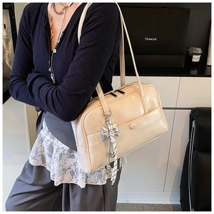 Close-up of beige oil-wax leather Boston bag with silver bow charm and pearl chain detail