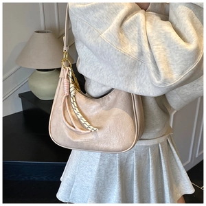 Detail of beige oil wax leather tote with woven knot charm and gold-tone hardware