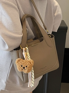 Minimalist litchi grain bucket bag in taupe with bear pendant and crossbody strap