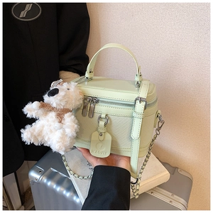 Detail of mint green woven box bag with plush bear charm and silver chain strap