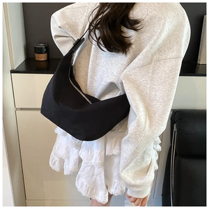 Detailed view of the black crescent hobo bag worn by model in a minimalist setting
