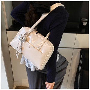 Close-up of cream PU leather Boston bag with silver bow charm and pocket detail
