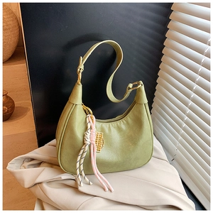 Detail of avocado green leather crescent bag with gold hardware and woven charm