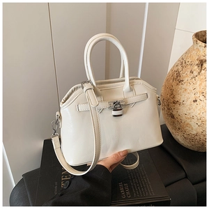 Detailed view of beige faux leather handbag with metallic clasp and round handle