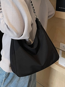 Minimalistische schwarze Nylon-Hobotasche mit silberner Kette am Modell für den Alltag
