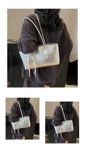 Detailed view of metallic silver bucket bag featuring branded embossed texture and knot tassel
