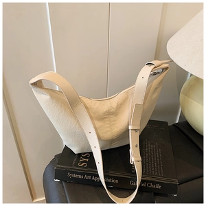 Detail of off-white crescent hobo bag with textured fabric and adjustable strap buckles