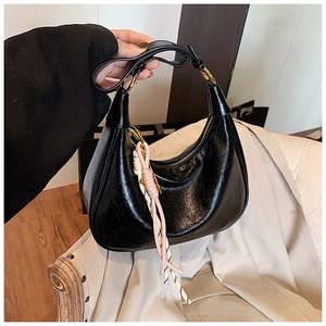 Detail of vintage black oil-wax leather hobo bag with gold hardware and striped silk scarf