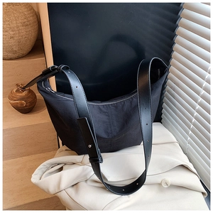 Detail of adjustable leather strap and silver metal buckle on black nylon hobo bag