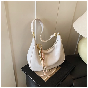 Detail of cream crescent tote bag with leather texture and gold metal ring hardware