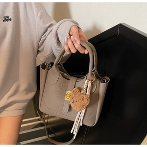 Close-up of gray lychee texture tote bag with gold hardware and plush bear charm