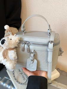 Elegant light gray textured box bag with top handle and cute plush bear accessory