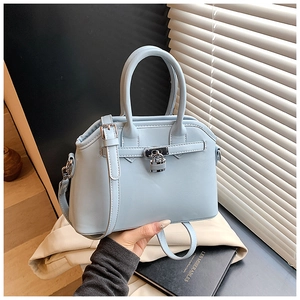 Detail of light blue shell bag in oil wax leather with decorative lock and hand strap