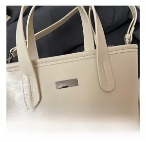 Detail showing high-quality silver metal hardware and stitching on cream tote bag