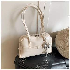 Detail of cream white faux leather Boston bag with silver bow charm and pocket buckle